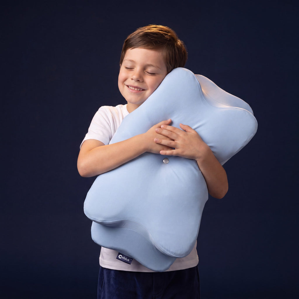Enfant souriant serrant dans ses bras son oreiller ergonomique Cellsius bleu