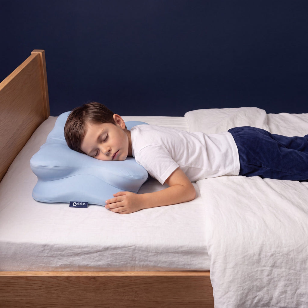 Enfant dormant paisiblement sur le ventre sur l'oreiller ergonomique de soutien de la nuque Cellsius