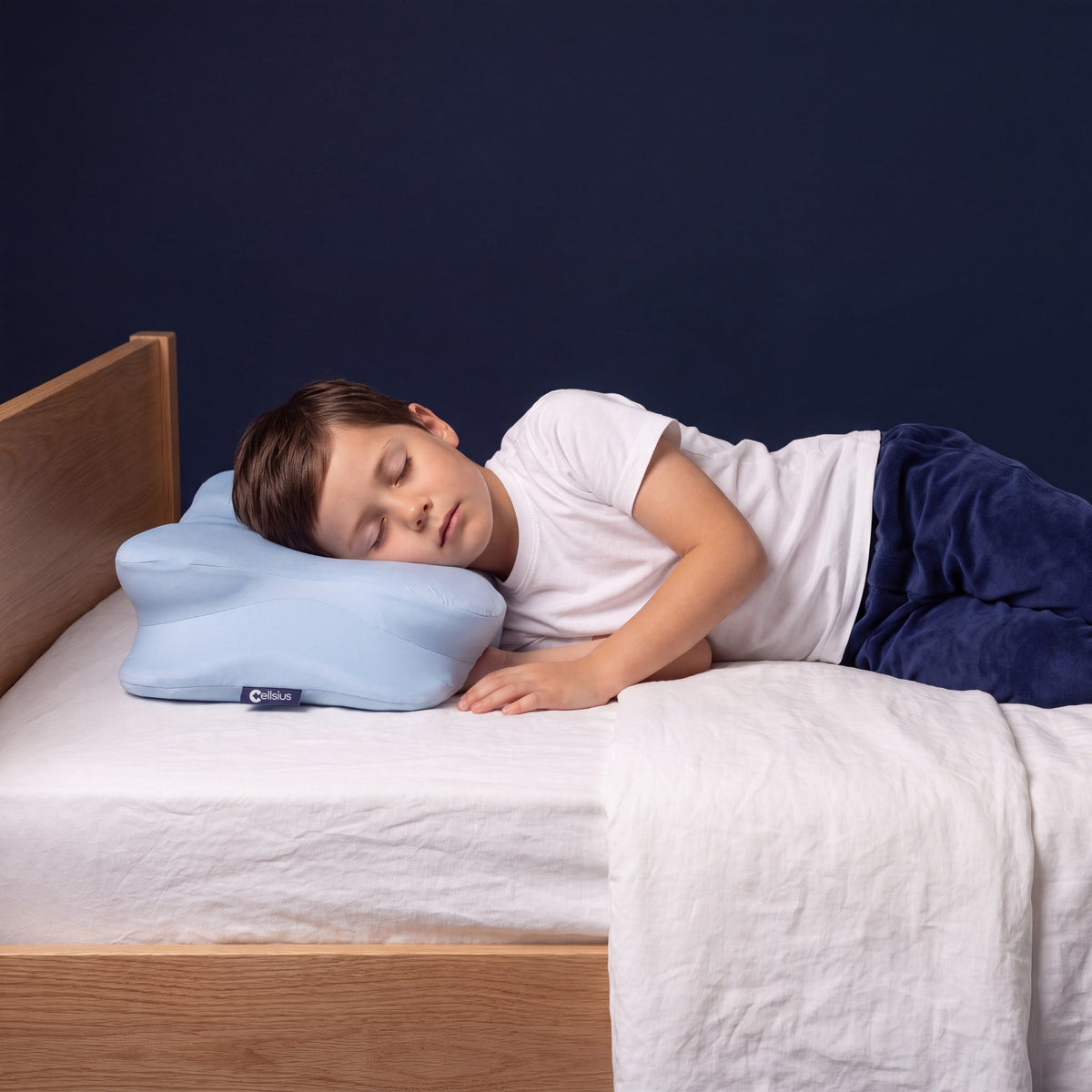 Jeune garçon endormi sur le côté, nuque soutenue par l'oreiller ergonomique Cellsius pour enfant